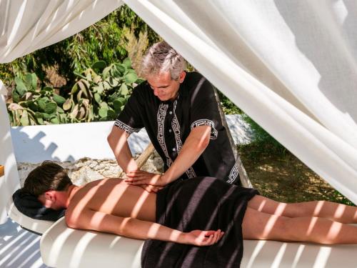 a man getting a back massage on a beach at Axel Beach Mykonos - Adults Only in Mýkonos City
