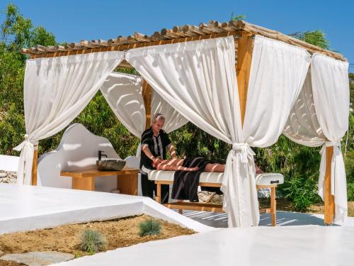a man sitting in a chair under a gazebo at Axel Beach Mykonos - Adults Only in Mýkonos City