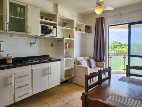 uma cozinha com armários brancos e uma sala de estar em Prédio à beira-mar, na melhor localização do Rio Vermelho. em Salvador