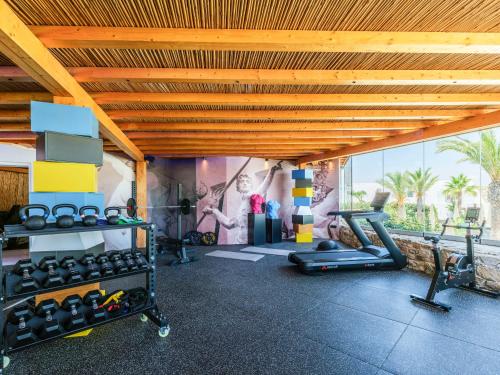 a gym with exercise equipment and a wall with a mural at Axel Beach Mykonos - Adults Only in Mýkonos City