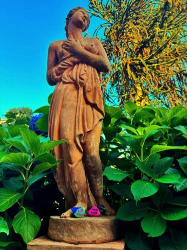 a statue of a woman standing in front of a bush at Villa Marchesa in Arona