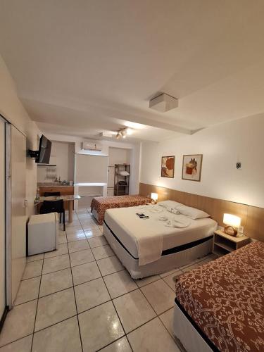 a hotel room with two beds and a desk at Mamaloo Pousada in Maceió
