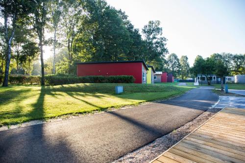 a road in a park with a red building at Landgoed Leudal in Haelen