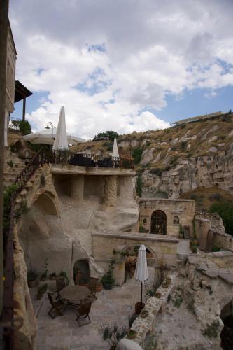 an outdoor patio with tables and umbrellas on a mountain at Potamia Cave Suites in Ortahisar