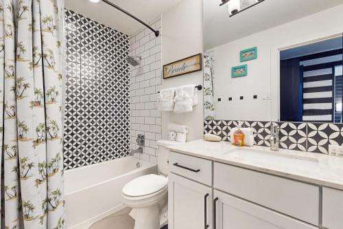 a white bathroom with a toilet and a shower at Toes In The Sand in Port Aransas