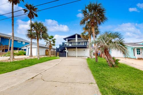 a street in front of a house with palm trees at Toes In The Sand in Port Aransas