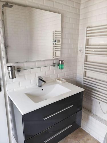 une salle de bain blanche avec un lavabo et un miroir dans l'établissement Magnifique maison avec extérieur, à Aulnay-sur-Mauldre