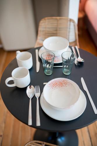a black table with plates and utensils on it at Villa Robs - Appartements tout confort, TV connectée, Haut débit, Localisation idéale - Courts séjours & Affaires in Caen