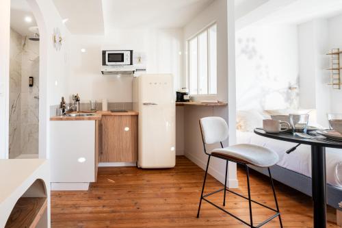 a small white kitchen with a table and a refrigerator at Villa Robs - Appartements tout confort, TV connectée, Haut débit, Localisation idéale - Courts séjours & Affaires in Caen