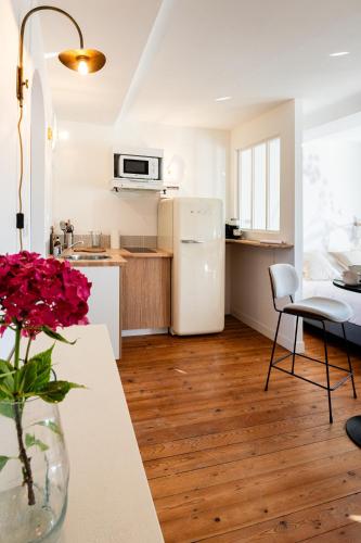 a kitchen with a refrigerator and a table with a vase of flowers at Villa Robs - Appartements tout confort, TV connectée, Haut débit, Localisation idéale - Courts séjours & Affaires in Caen