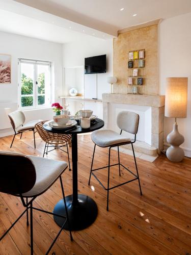 a living room with a table and chairs and a fireplace at Villa Robs - Appartements tout confort, TV connectée, Haut débit, Localisation idéale - Courts séjours & Affaires in Caen