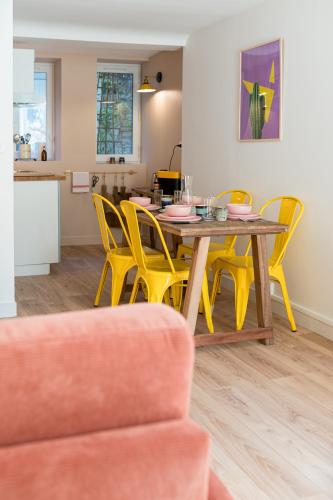 a dining room with a table and yellow chairs at Villa Robs - Appartements tout confort, TV connectée, Haut débit, Localisation idéale - Courts séjours & Affaires in Caen