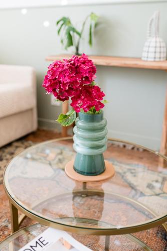 a vase with pink flowers sitting on a glass table at Villa Robs - Appartements tout confort, TV connectée, Haut débit, Localisation idéale - Courts séjours & Affaires in Caen
