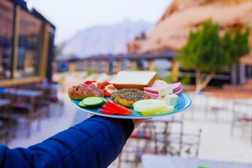 a person holding a plate with food on it at ROSELLA Wadi Rum in Disah