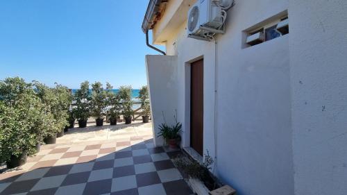 a white building with a door and a checkered floor at CAMERETTA SUL MARE con OMBRELLONE in Lido Di Fondi