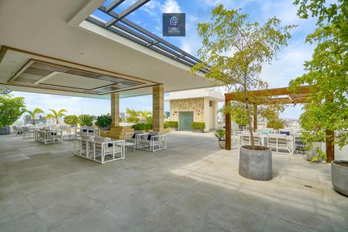 a patio with white chairs and tables and trees at Monaco Residences Piantini in Santo Domingo