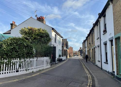 an empty street with buildings and a person walking down the street at Flat in the heart of Leigh on Sea less than 2 miles from the beach in Southend-on-Sea