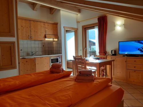 cocina con 2 camas, mesa y TV en Chalet Beatrice, en Livigno