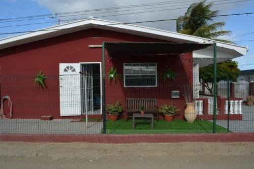 a red house with a fence in front of it at Grateful Corner Apartment Curaçao in Willemstad