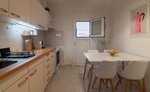 a kitchen with a white table and white chairs at Filoxenia DD in Agios Rokkos