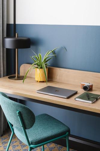 a desk with a laptop and a green chair at voco Belfast by IHG in Belfast