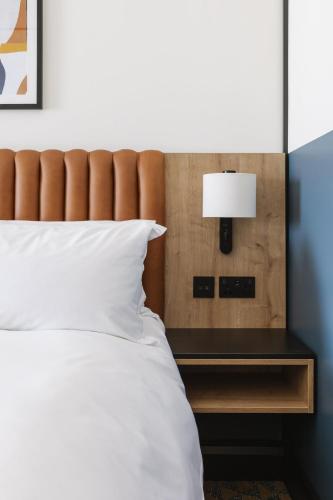 a bedroom with a bed and a table with a lamp at voco Belfast by IHG in Belfast