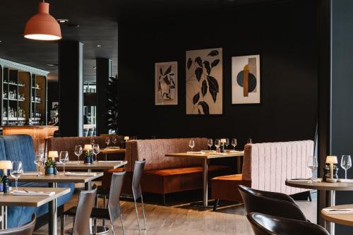 a restaurant with tables and chairs and a black wall at voco Belfast by IHG in Belfast