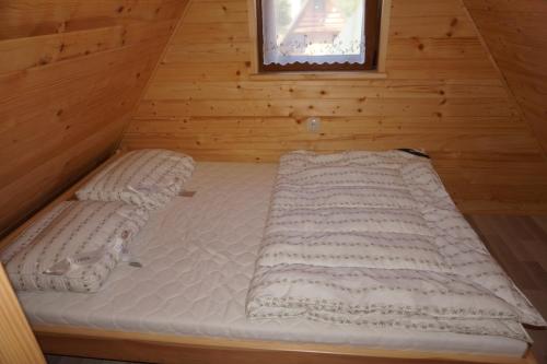 a bed in a wooden cabin with a window at Domki nad Soliną - Bieszczadzka Osada 512-823-385 in Solina