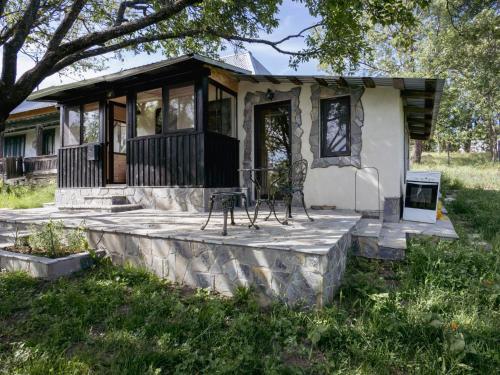 una piccola casa con portico e tavolo e sedie di Casa din sat a Marginea Pădurii