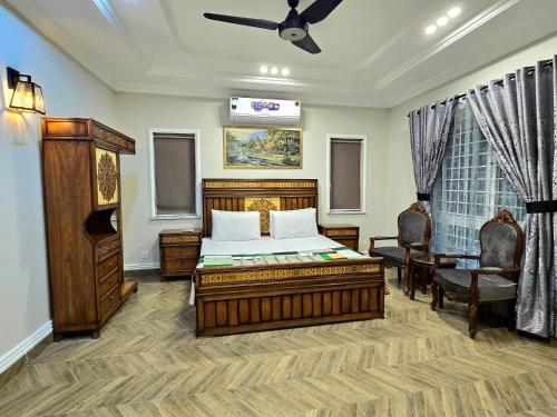 a bedroom with a bed and two chairs and a ceiling at Stylish Independent 3-Bedroom House in Bahria Town in Rawalpindi