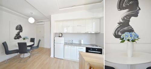 a kitchen with white cabinets and a table with a vase of flowers at Pearl Shell Apartments in Kotor