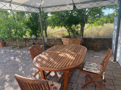 a wooden table and chairs under an umbrella at Alloggio turistico Villa Camelia Lavinio in Anzio
