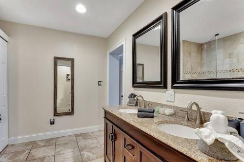 a bathroom with two sinks and two mirrors at Stunning Lake House with Heated Pool & Ping Pong! in Lutz