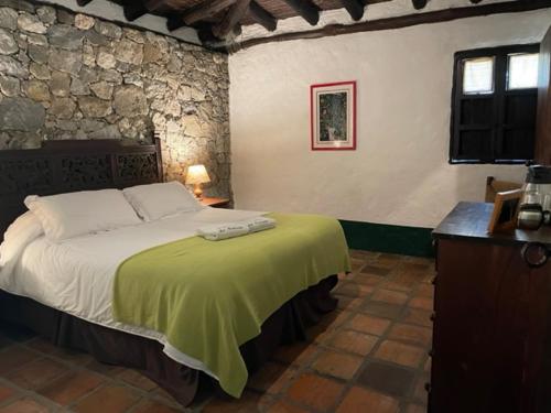 a bedroom with a large bed with a green blanket at Estancia La Cañada in Mérida