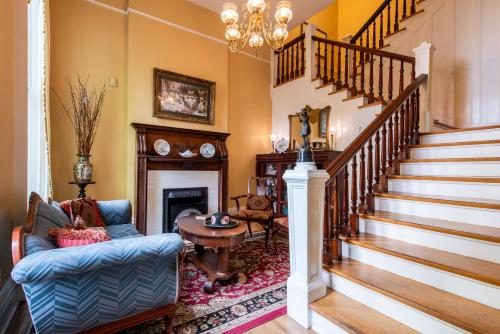 a living room with a staircase with a chair and a fireplace at DuPont Mansion Bed & Breakfast in Louisville