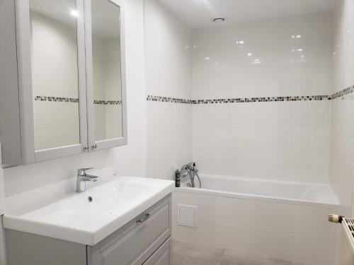 a white bathroom with a sink and a bath tub at Grande maison - village de Noyers - 5 chambres in Noyers-sur-Serein