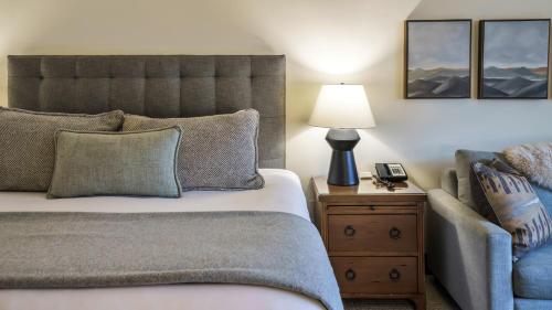 a bedroom with a bed and a lamp and a chair at 378 Lodge At Spruce Peak Ski In Ski In Ski Out King Studio By Stowe Mountain Rentals in Stowe