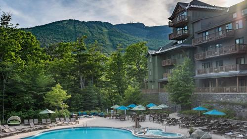 a view of a hotel with a pool and tables and chairs at 378 Lodge At Spruce Peak Ski In Ski In Ski Out King Studio By Stowe Mountain Rentals in Stowe