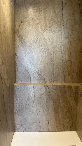 La salle de bains est pourvue d'une douche en marbre et d'une étagère. dans l'établissement Duplex Familial au Cœur de Dinard, à Dinard