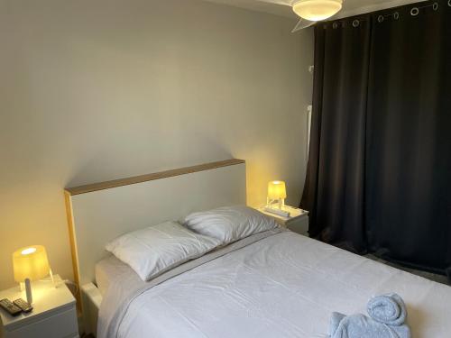 - une chambre avec un lit blanc, deux lampes et une fenêtre dans l'établissement La Cardonille appartement avec patio, à Montpellier