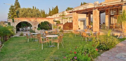a patio with tables and chairs in a yard at Eliofos Elegant Maisonettes in Polis Chrysochous