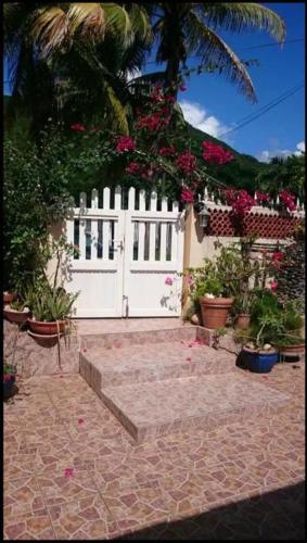 a white fence with a white gate and some flowers at Casa Lof in Case-Pilote