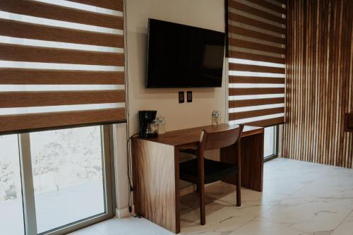 a room with a desk and a television on the wall at La Cascada Hotel Boutique in Juanacatlán