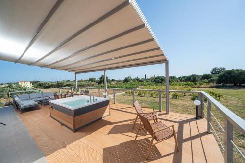 a patio with a hot tub and chairs on a deck at Villa Sorina Kefalonia in Svoronata