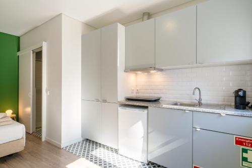 a kitchen with white cabinets and a sink at Oporto Seaside Village - Casa Bosque in Matosinhos