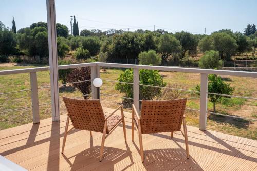 two chairs on a balcony with a view of a field at Villa Sorina Kefalonia in Svoronata