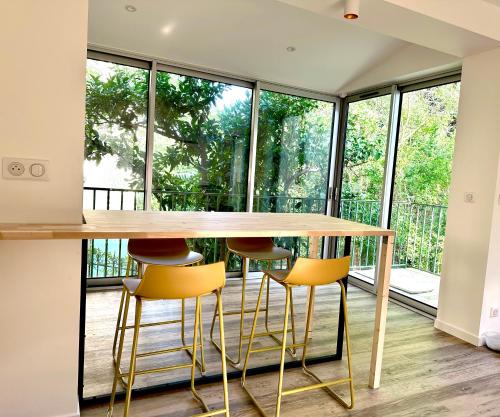 une cuisine avec une table en bois et des tabourets jaunes dans l'établissement Appartement avec jardin privé à 2min de la plage, à Banyuls-sur-Mer