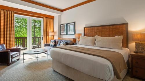 a bedroom with a large bed and a living room at 1204 Lodge At Spruce Peak Ski In Ski In Ski Out King Studio By Stowe Mountain Rentals in Stowe