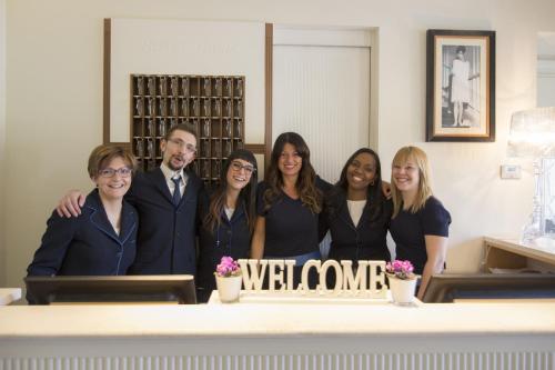 a group of people standing around a table with a welcome sign at Hotel Italia in Siena