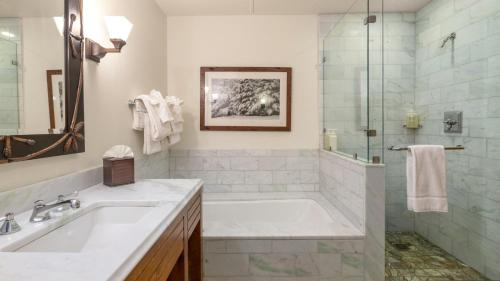 a bathroom with a tub and a sink and a shower at 145 Lodge At Spruce Peak Ski In Ski In Ski Out King Studio By Stowe Mountain Rentals in Stowe